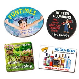 Four eco-friendly MDF magnets in various shapes featuring colourful designs and logos, with text and contact information.