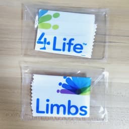 Two packaged lens cloths featuring colourful designs and branding, one labelled "4 Life" and the other "Limbs".