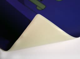 A purple mouse mat with a textured surface, featuring a white, rolled edge. It has a logo visible in the design.