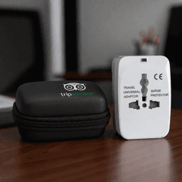 A white travel universal adaptor with a surge protector, placed alongside a black zip case featuring a logo.