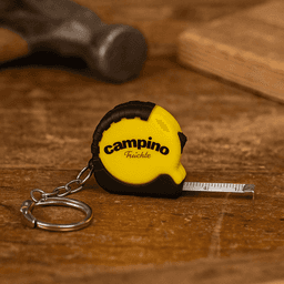 A mini tape measure in yellow and black with a keychain attachment, resting on a wooden surface.