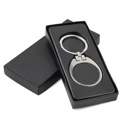 A black leather keychain with a silver metal frame, presented in a sleek black box.