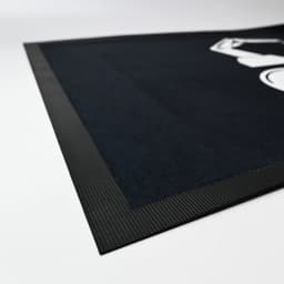A black mat with a textured border, featuring a graphic design in a contrasting colour.