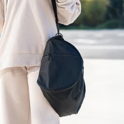 A black duffle bag with a sleek design featuring a shoulder strap and a zip pocket.
