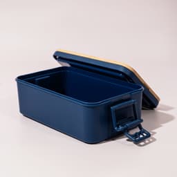 A navy blue lunch box with a wooden lid and a handle, featuring a spacious interior. It has a logo on the side.