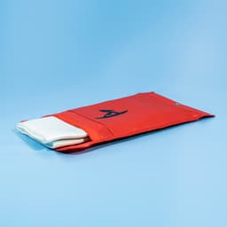 A red pouch containing a white fiberglass emergency fire blanket, featuring a logo.