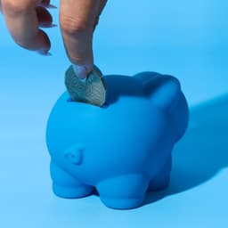 A blue pig-shaped money box, designed with a slot for coins.