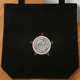 A black tote bag featuring a circular logo set within a star design.