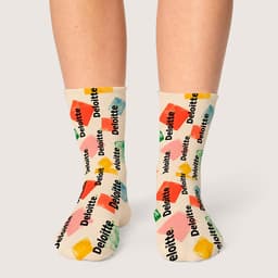 Colourful socks featuring various shapes and a logo pattern in green, yellow, red, and blue against a cream background.