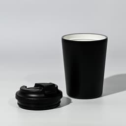 A black travel cup with a removable lid, featuring a sleek design and a contrasting inner colour.