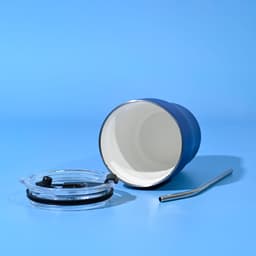 A blue tumbler with a straw, featuring a clear lid and a stainless steel straw beside it.