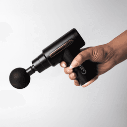 A black massage gun with a spherical attachment held in a hand, featuring a sleek design and a logo.