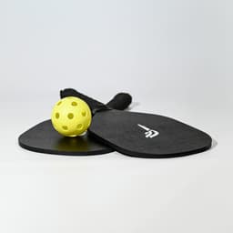 A black pickleball set featuring two paddles and a yellow ball, with a logo on the paddles.