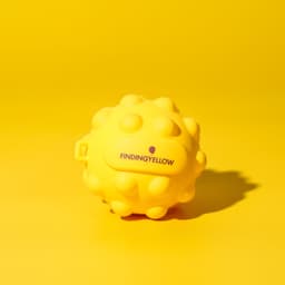 A yellow stress ball with a textured, spiky surface, featuring a small logo on it.