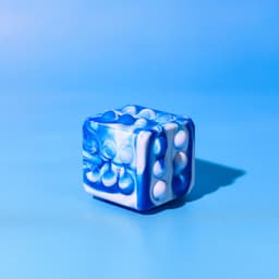 A blue and white Popper Cube with raised bubbles on its sides, set against a light blue background.