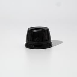 A black speaker with a rounded design, featuring a smooth surface and a small branding element at the front.
