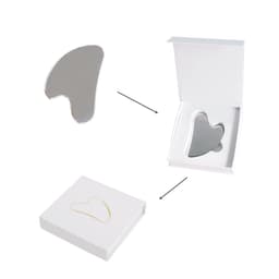 A stainless steel gua sha massage tool in a white box, featuring a sleek and reflective surface.