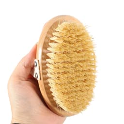 A sisal wooden brush held in a hand, featuring a light wooden base and natural bristles.