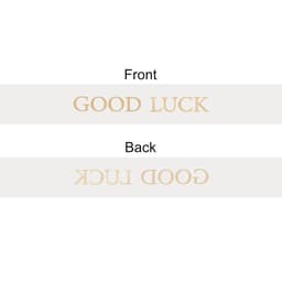 A soft ribbon in a light colour featuring the words "GOOD LUCK" printed on both sides. It has a simple branding logo.