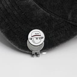 A 25mm golf ball marker featuring a cartoon sheep wearing a hat, attached to a silver clip on a dark cap.