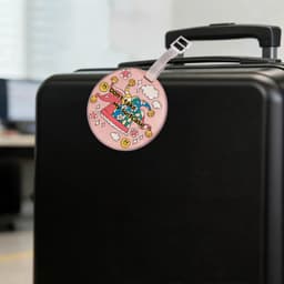 Acrylic luggage tag with a pink design, attached to a black suitcase handle, featuring a logo.