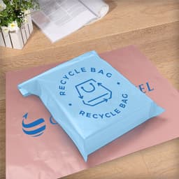 A light blue self-sealing plastic mailing bag on a pink background, featuring a logo.