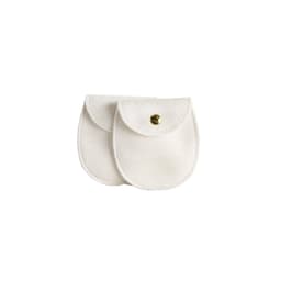A pair of oval white velvet jewelry pouches with gold snap closures and a logo on one.
