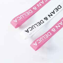 Ribbed fabric ribbon in pink and white, featuring a logo, suitable for various decorative uses.