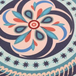 A round trivet featuring a floral design in turquoise, pink, and navy blue, with decorative patterns.