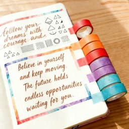 Washi tape in various colours—red, orange, purple, and blue—adorns the edge of a notebook with motivational quotes.