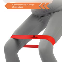 A red latex-free TPE fitness resistance band positioned around the thighs of a person wearing grey leggings.