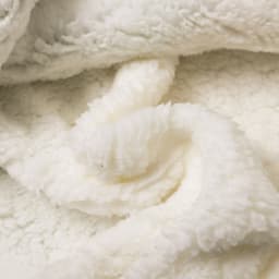 A soft, cream-coloured wearable blanket made from 100% polyester with a plush, textured surface and folds.