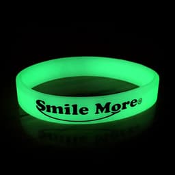 A green glow in the dark wristband with a logo, displayed against a dark background.