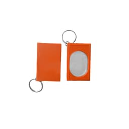 An orange pet training clicker with a keyring attachment and an oval mirror on one side.