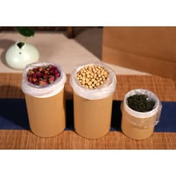 Large paper cylinder boxes in brown with transparent lids, containing dried flowers, beans, and herbs.
