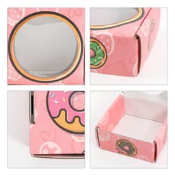 A small pink gift box featuring a round window and a playful donut print. The box has a logo and is rectangular in shape.