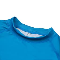 A bright blue UPF 50+ rashie featuring long sleeves and a high collar, with a tag visible inside.