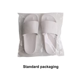 White PVC slides packaged in a clear plastic bag. The footwear has a simple design with two wide straps.