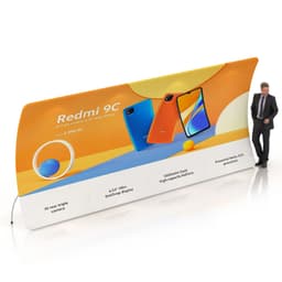 A U-shaped fabric display wall in orange and white featuring smartphone images and a logo, with a person standing beside it.