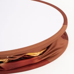A round, backlit LED display with a smooth, white surface and an orange fabric border, featuring a hidden storage area.