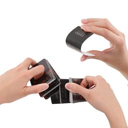 Custom playing cards in black with a logo, being held and fanned out by hands.