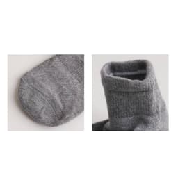 A pair of grey socks with a gripper design, featuring a close-up view of the toe and cuff sections.