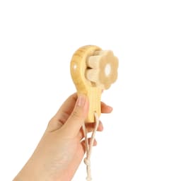 A wooden facial cleansing brush shaped like a flower, featuring a light wood finish and a string handle.
