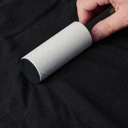 A lint remover with a grey handle, designed for removing lint and debris from fabric surfaces.