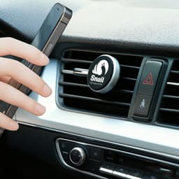 A clip-on car phone holder in silver attached to a car air vent, with a smartphone being positioned near it.
