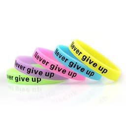 A collection of glow in the dark silicone wristbands in various colours with the phrase "Never give up" printed on them.
