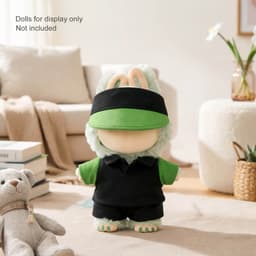 A plush doll racing suit set in green and black, displayed on a soft rug with a teddy bear nearby.