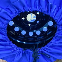 A blue spare tyre cover with a black inner ring features holes and a drawstring for securing the cover.