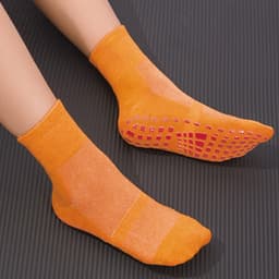 Bright orange gripper socks featuring textured soles and ankle height, designed for improved traction and comfort.