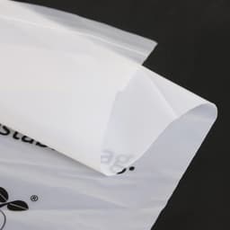 A transparent, biodegradable self-adhesive bag with a smooth surface and a subtle logo in the corner.